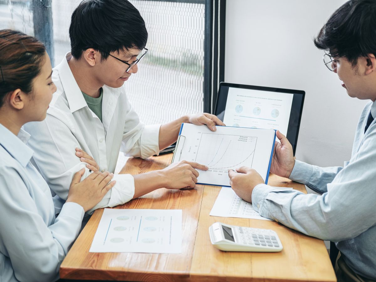 A JEM accountant reviewing a report with clients at a warm wooden table