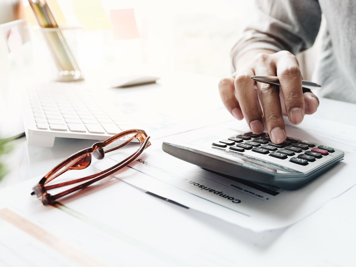 Close-up of an accountant reconciling figures with a calculator and laptop
